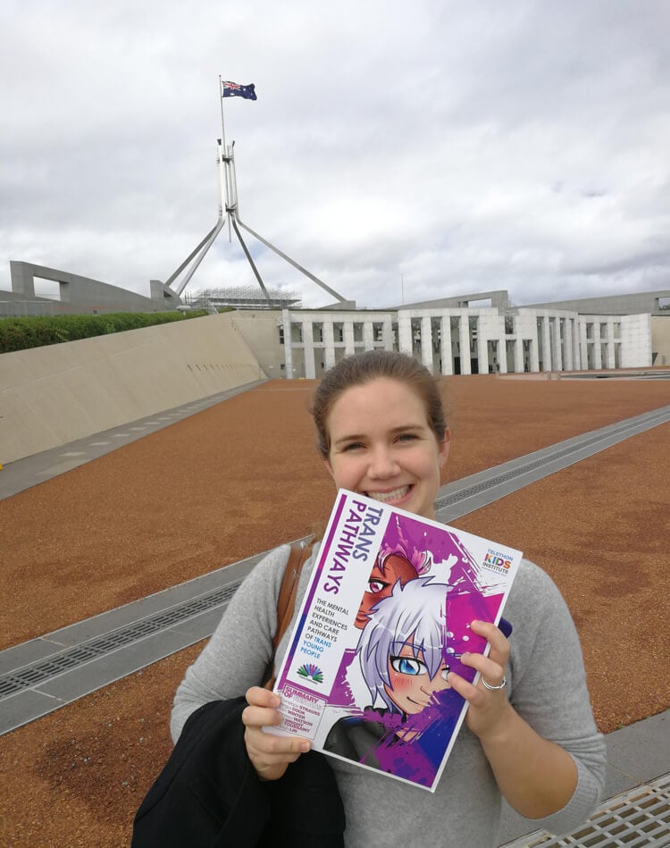 Lead author of Trans Pathways Penelope Strauss holds a copy of the report outside Parliament House in Canberra